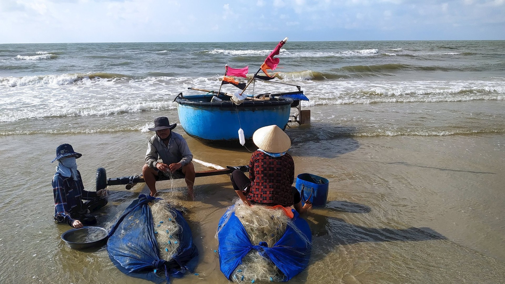 Những ngư dân ngồi xếp lưới trong nắng sớm, chờ đến đêm lại ra khơi.