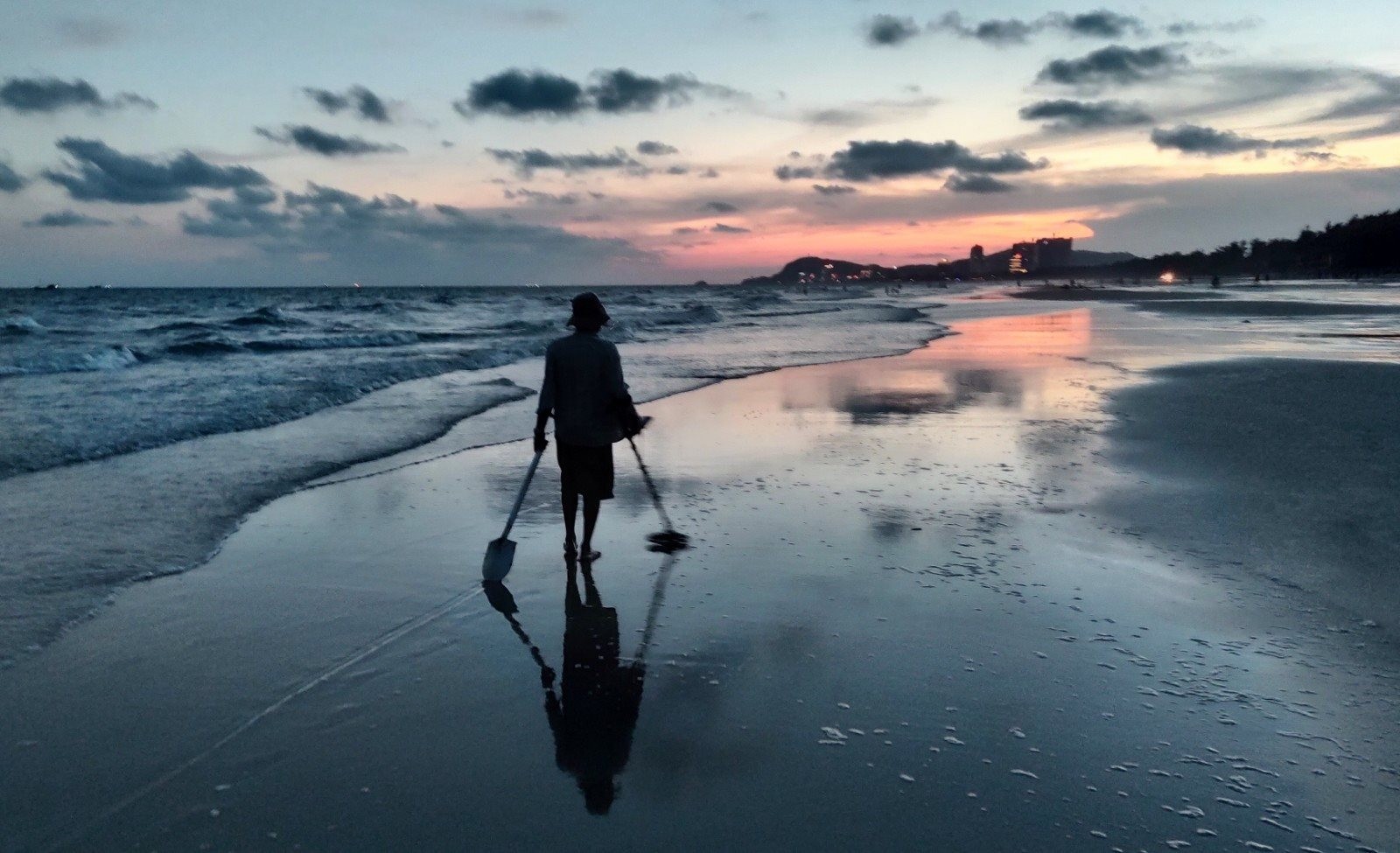 Cả bãi biển rộng chỉ còn người thợ dùng máy rà kim loại, tìm vật dụng ai đó đánh rơi hoặc sóng biển cuốn từ xa vào bờ.