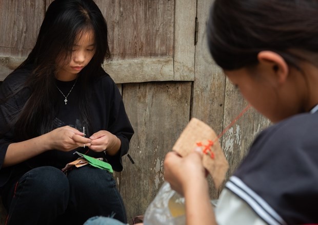 Các em gái dân tộc Mông học thêu đắp vải màu. Ảnh: Nam Thái – TTXVN