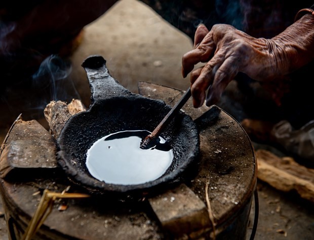 Sáp ong được đun trên bếp than dùng để vẽ lên vải lanh. Ảnh: Nam Thái – TTXVN