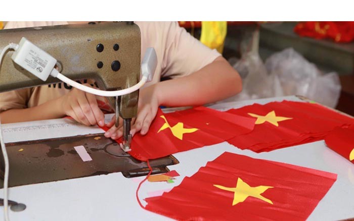 Hộ gia đình anh Nguyễn Văn Phục, hàng chục nhân công vẫn đang hối hả, rộn ràng với công việc cắt, may, phết sơn, in chữ...ràng với công việc cắt, may, phết sơn, in chữ..