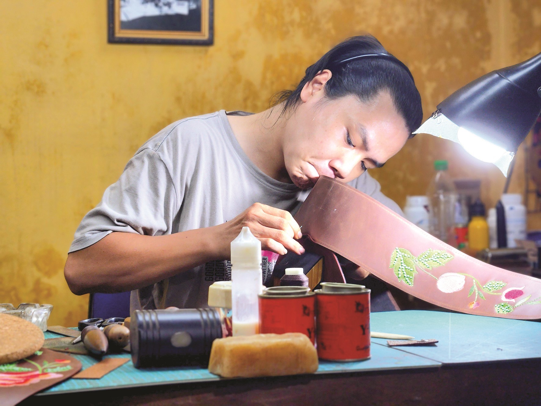 Người trẻ địa phương may da thủ công. Người trẻ địa phương may da thủ công.