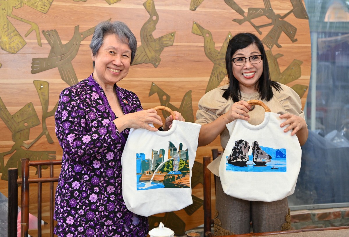 Hai phu nhân cầm túi có tranh vẽ các biểu tượng du lịch của hai nước, gồm hòn Trống Mái vịnh Hạ Long và Công viên Sư tử biển ở Singapore. Hai phu nhân cầm túi có tranh vẽ các biểu tượng du lịch của hai nước, gồm hòn Trống Mái vịnh Hạ Long và Công viên Sư tử biển ở Singapore.