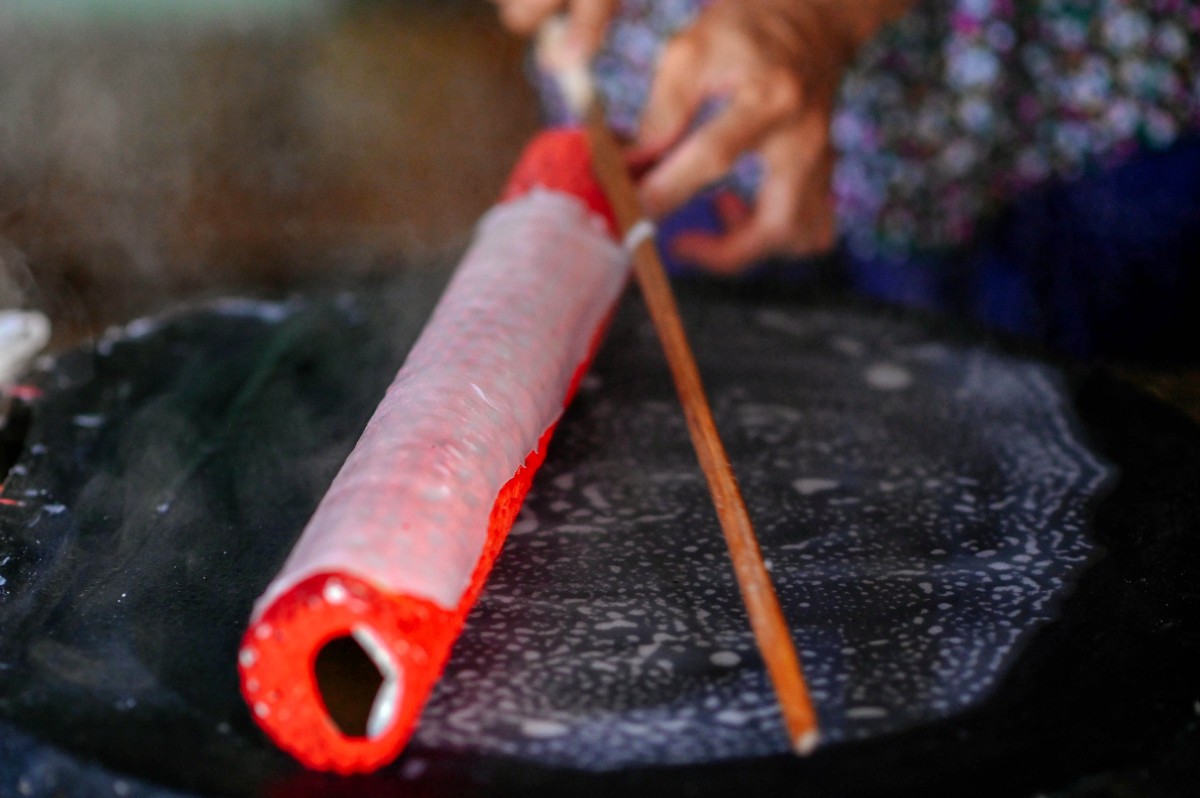  Bánh được cuộn bằng ống tre có bọc lớp vải khỏi mặt chảo hấp