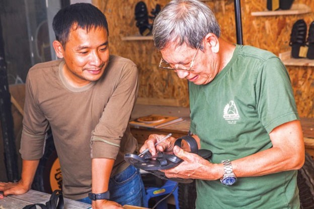 Ông Phạm Quang Xuân (bên phải) và anh Nguyễn Tiến Cường là hai nghệ nhân có đam mê đặc biệt với nghề làm dép lốp thủ công.