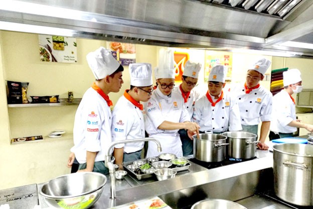 Người nước ngoài hào hứng khi được nghệ nhân Châu hướng dẫn cách chế biến món ăn Việt Nam. 