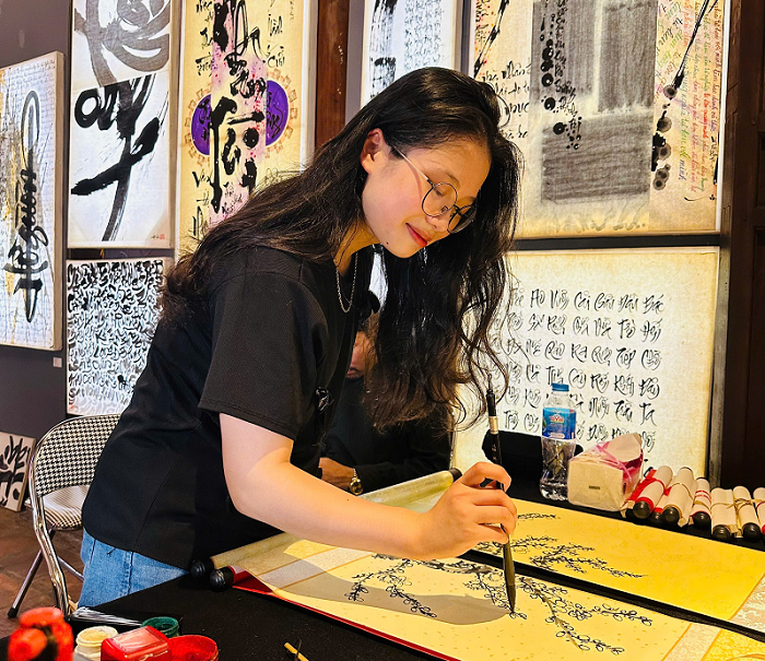 Nữ sinh viên trải nghiệm viết thư pháp trong không gian triển lãm  Nữ sinh viên trải nghiệm viết thư pháp trong không gian triển lãm