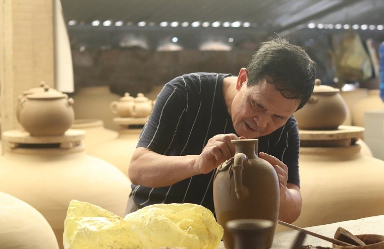 Nghệ nhân Trịnh Văn Dũng - Chủ nhiệm HTX Gốm Gia Thủy cho biết: Gia đình ông có 3 đời theo nghề truyền thống. Gốm Gia Thủy tuy có trải qua những giai đoạn khó khăn nhưng với tình yêu nghề, ông Dũng quyết tâm giữ lửa. Đến nay, các lò gốm của HTX cho ra lò khoảng 2.400 sản phẩm mỗi tháng, doanh thu ước đạt lên tới hàng tỷ đồng mỗi năm. Hiện tại, các lò gốm của HTX đang có khoảng 50 lao động làm việc thường xuyên với mức lương 7 - 8 triệu đồng/người/tháng. Ngoài ra, để bảo tồn nghề truyền thống, HTX còn nhận dạy nghề miễn phí cho các thanh niên trong xã. Ảnh: Đình Minh Nghệ nhân Trịnh Văn Dũng - Chủ nhiệm HTX Gốm Gia Thủy cho biết: Gia đình ông có 3 đời theo nghề truyền thống. Gốm Gia Thủy tuy có trải qua những giai đoạn khó khăn nhưng với tình yêu nghề, ông Dũng quyết tâm giữ lửa. Đến nay, các lò gốm của HTX cho ra lò khoảng 2.400 sản phẩm mỗi tháng, doanh thu ước đạt lên tới hàng tỷ đồng mỗi năm. Hiện tại, các lò gốm của HTX đang có khoảng 50 lao động làm việc thường xuyên với mức lương 7 - 8 triệu đồng/người/tháng. Ngoài ra, để bảo tồn nghề truyền thống, HTX còn nhận dạy nghề miễn phí cho các thanh niên trong xã. Ảnh: Đình Minh