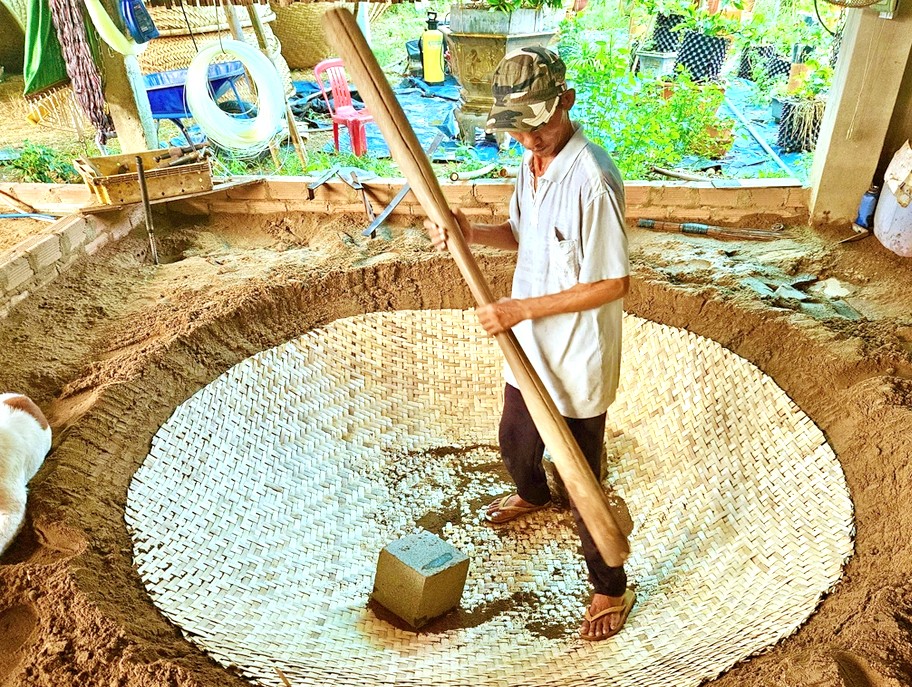 Mê thúng sau khi đan được đặt vào một khuôn đất đã đào sẵn dùng chiếc chày khổng lồ nện xuống đáy thúng để tạo hình