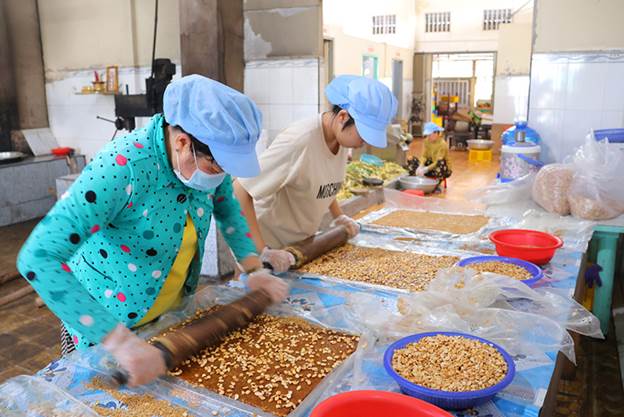 Ngọt ngào hương vị kẹo khóm Tân Phước Đậu phộng béo giòn được những người thợ nhanh tay cán hòa lẫn vào mẻ kẹo khóm lúc còn nóng