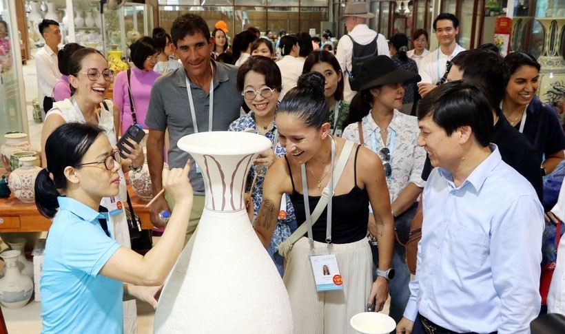 Các vị khách quốc tế trải nghiệm vẽ hoa văn lên các bình gốm thô.