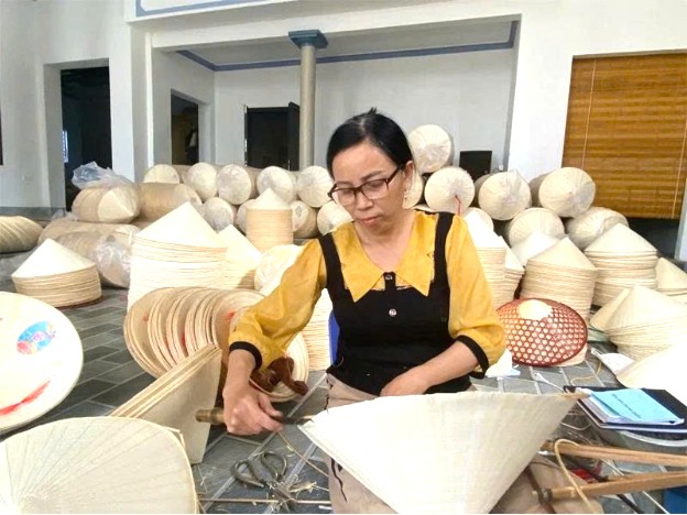 Bà Ngô Thị Toan, chủ cơ sở sản xuất nón lá Hùng Toan   hoàn thiện thành phẩm. Ảnh Tăng Thúy