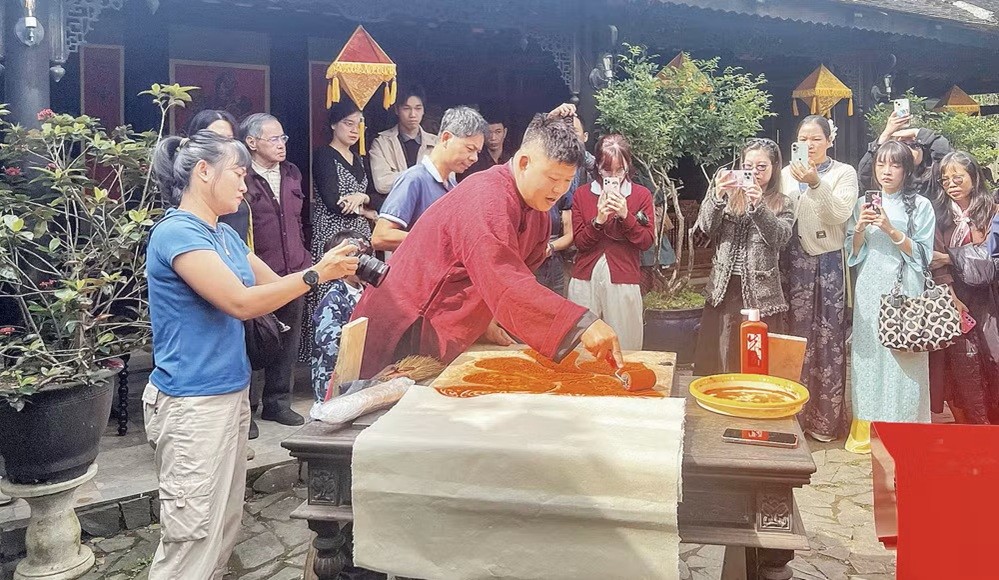 Nghệ nhân Nguyễn Công Đạt thực hiện in liễn làng Chuồn trong không gian Ngự Hà Viên, Huế. (Ảnh: MẠNH HÀO)