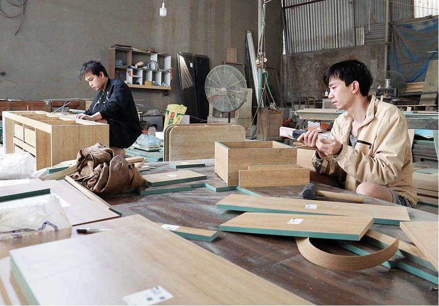 Anh Lê Thế Huy (phải), chủ một xưởng mộc ở làng nghề Phú An (xã Hát Môn) góp phần thúc đẩy phát triển nghề truyền thống của địa phương. Ảnh: Nguyễn Mai