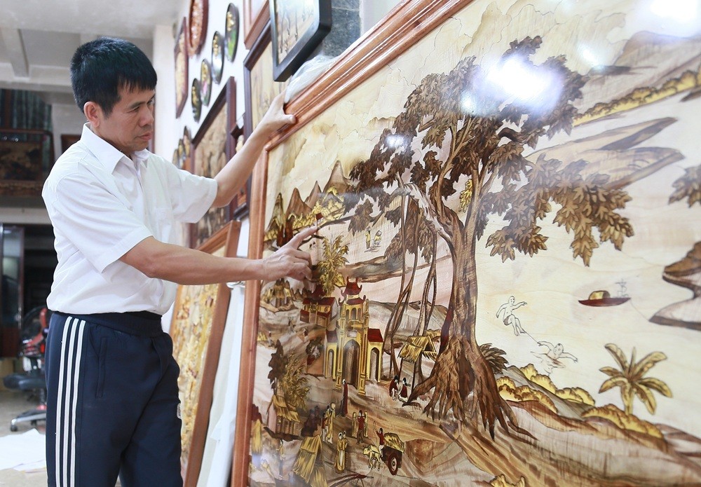 Nghệ nhân Ưu tú Nguyễn Văn Hùng tỉ mẩn hoàn thiện bức tranh ghép gỗ.