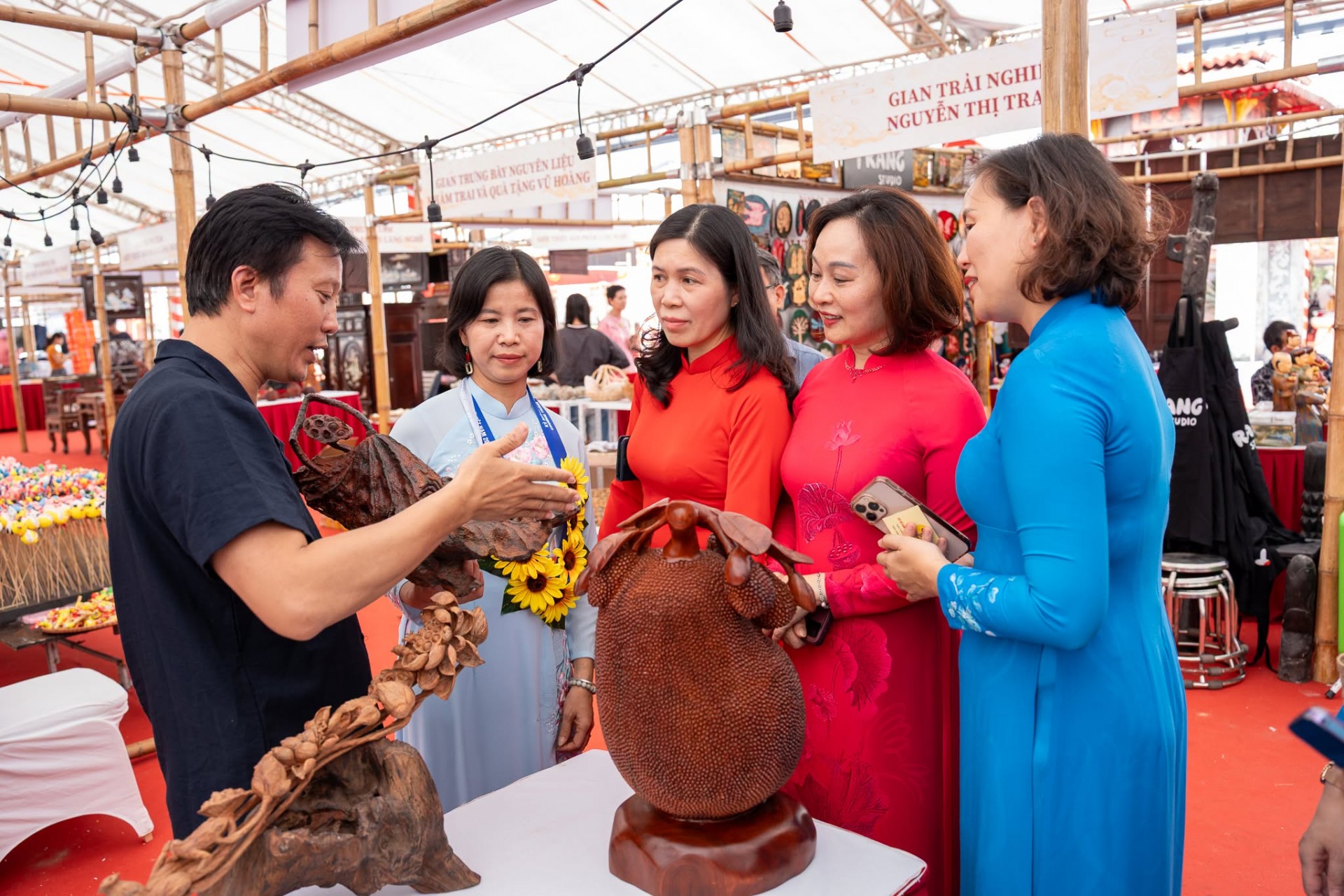 Nữ nghệ nhân Dương Thị Thu Hồng (người thứ 2 từ trái sang), nghề Chế tác gỗ mỹ nghệ cùng chồng giới thiệu sản phẩm tới các đại biểu.